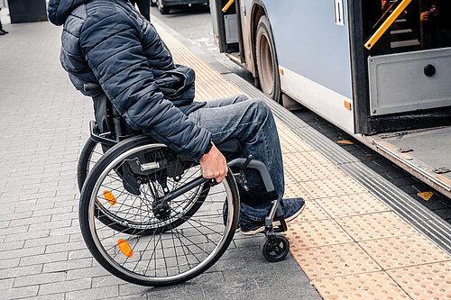 A wheelchair user approaches a bus door